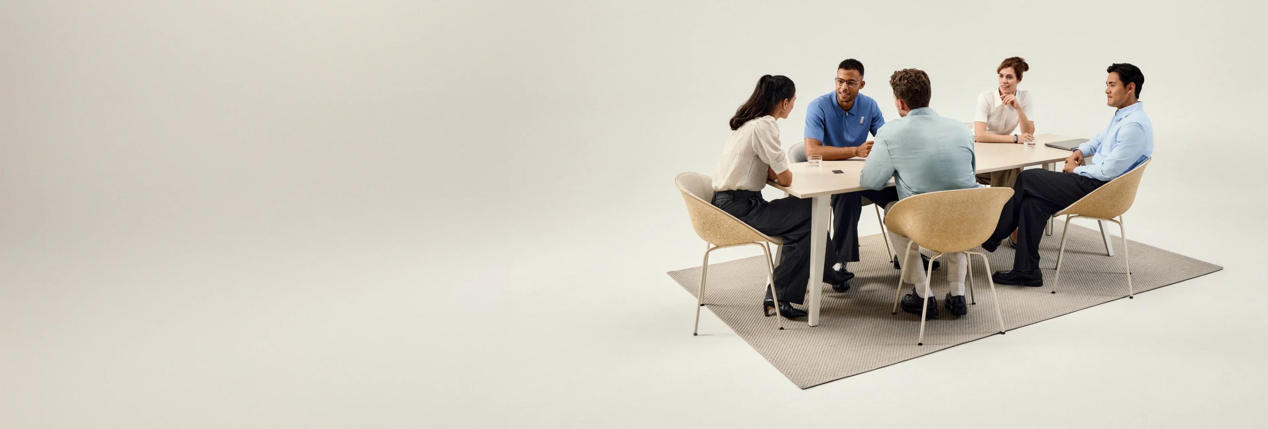Five professionals are seated around a light wooden table on a gray rug, engaged in a meeting, with a Plaud AI voice recorder