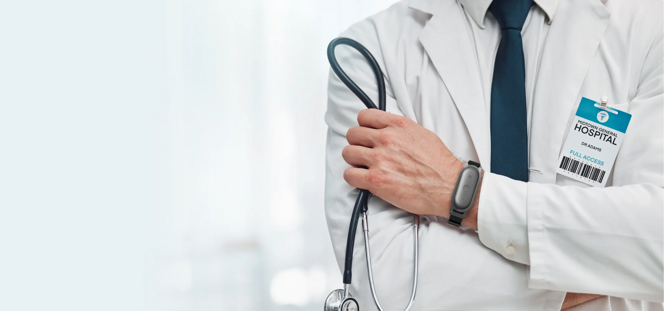 Doctor in lab coat holding stethoscope, wearing a dark gray Plaud NotePin on a wristband.