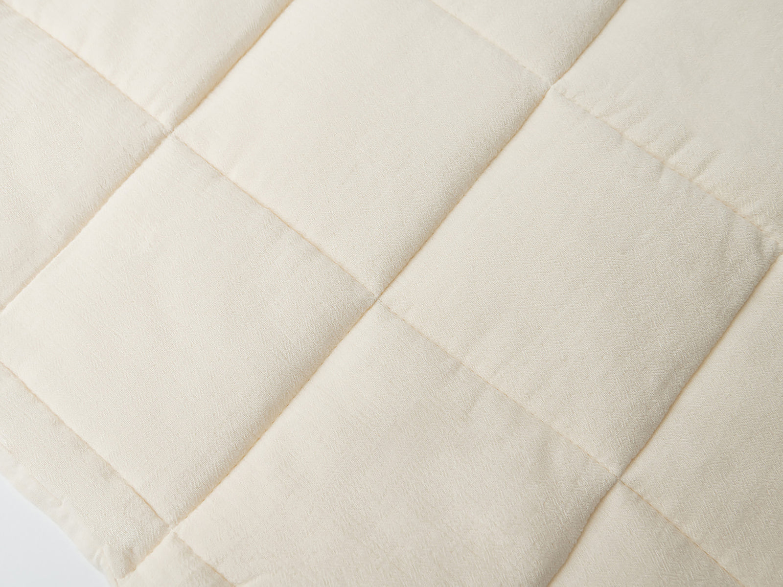 Close up of Buttermilk Aire Bamboo Box Quilt Euro Sham. The sham is resting on a bed in a bedroom