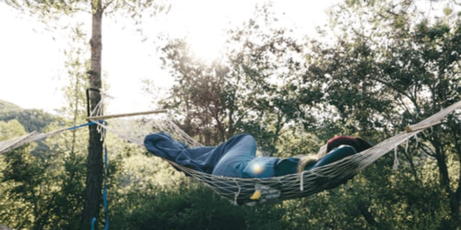 A person laying down with a hammock in the forest