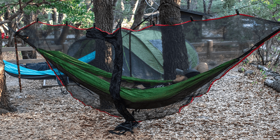 Two hammocks one with a bug net one without a bug net in the forest