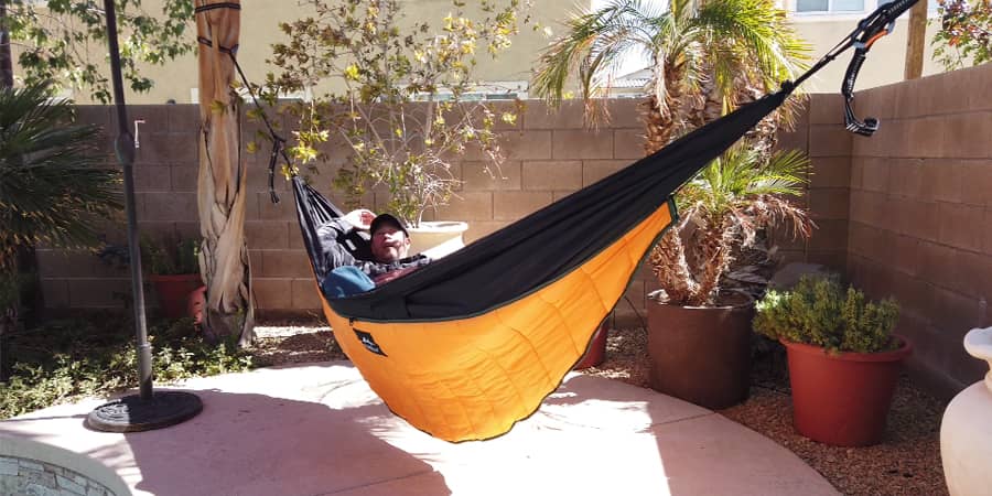 Man laying in his orange hammock in his backyard