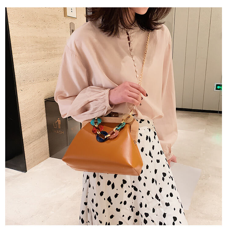 ein Model mit einer braunen Clutch aus Holz