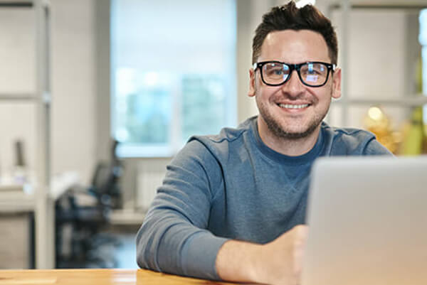 A man with glasses is looking at a computer