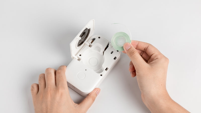 Hand installing a label roll into the open Phomemo D30 label printer