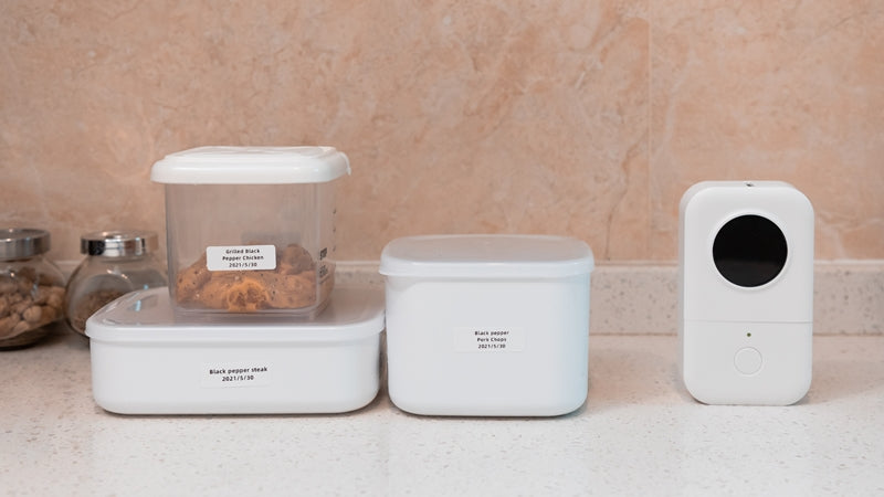 Phomemo D30 label printer and labeled food storage containers on a kitchen counter