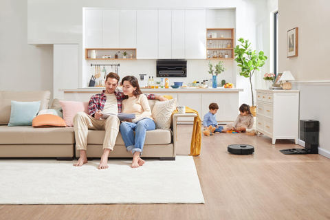 Les parents et les enfants lisent et jouent dans le salon, tandis que l'aspirateur Roborock (Q7 Max) de la maison nettoie automatiquement le parquet.