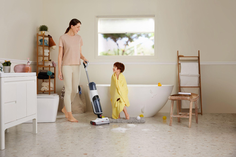Maman utilise l'aspirateur-laveur de Roborock (Dyad Pro)pour nettoyer l'eau et les bulles sur le sol de la salle de bain.