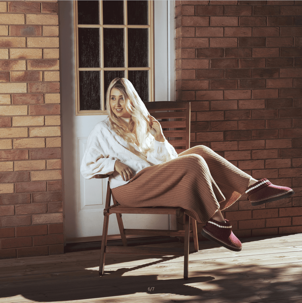 The model sits on the chair in red boots