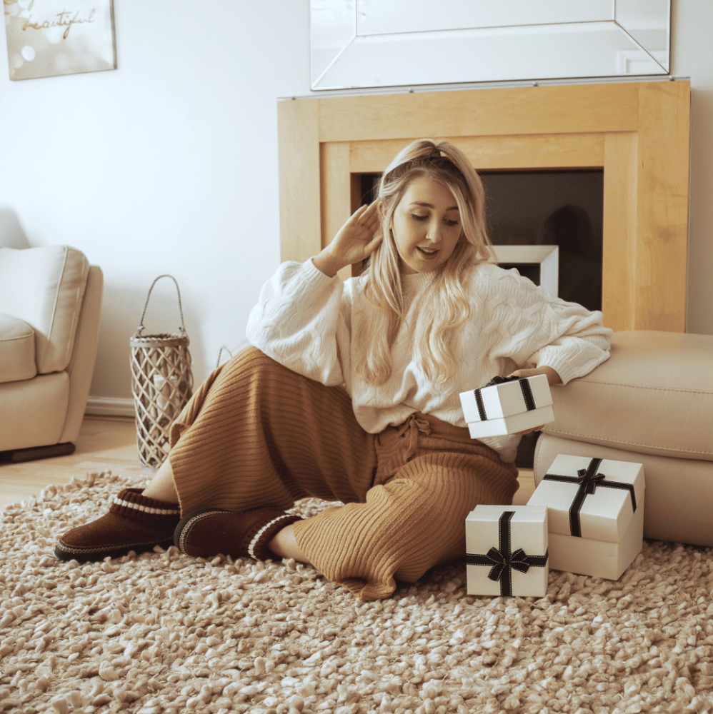 The model sits on the carpet in brown boots