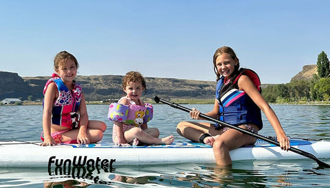 3 kids sitting on the inflatable paddle board