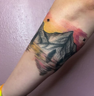 watercolor mountain tattoo on the forearm