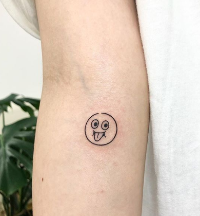 Small smiley face tattooed on the upper arm