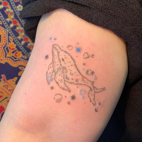 small whale arm tattoo with bubbles