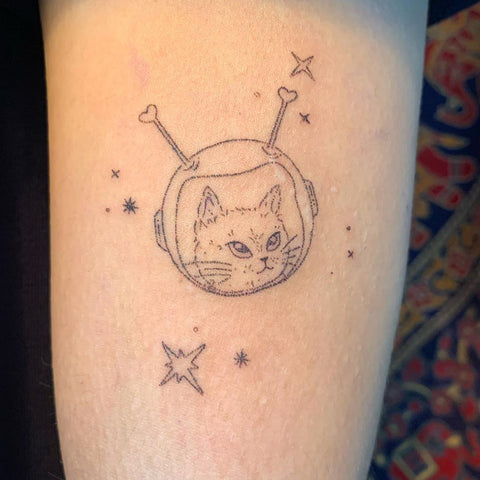 small cat astronaut arm tattoo