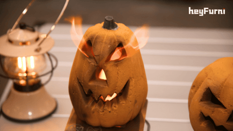 a yellow ceramic carved pumpkin with heyfurni tabletop fireplace, the fire come through the eyes, mouth and nose