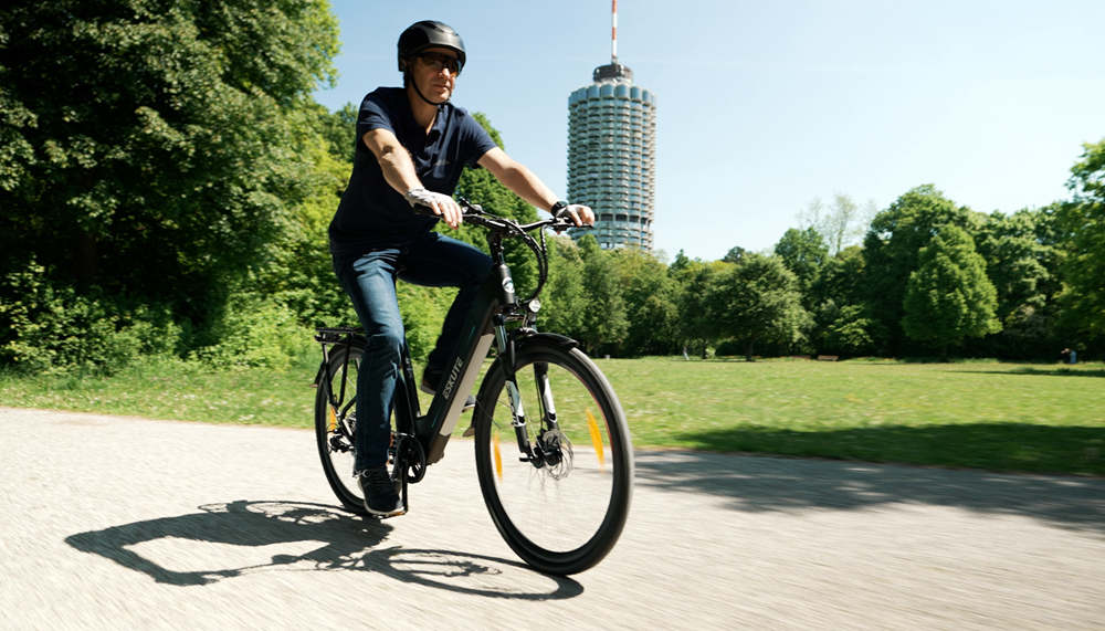 a man with helmet is riding Eskute Polluno electric city bike on the road