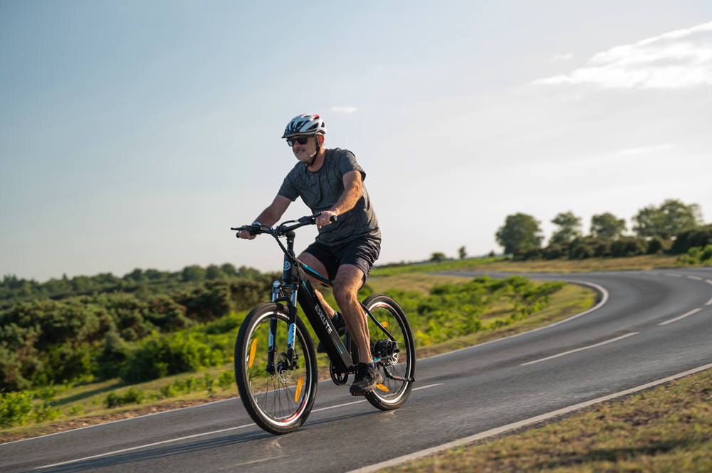 a man with helmet is riding netuno ebike on the downhill road