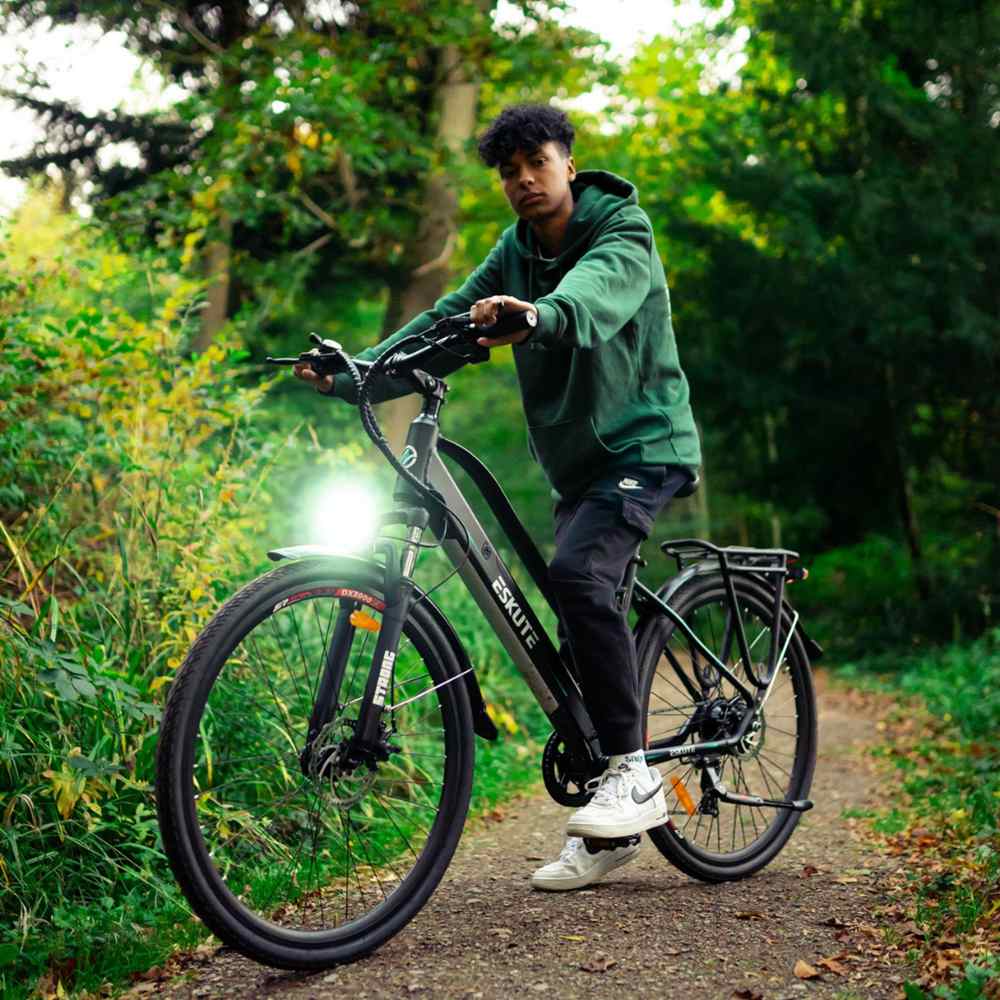 a young man sits on his hybrid ebike with the front light on