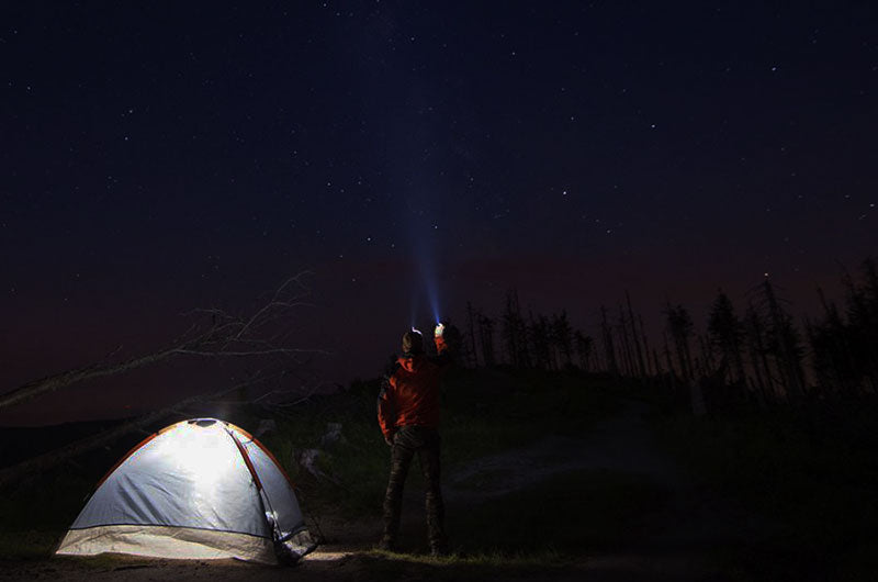 A camping man holds a LED flashlight.