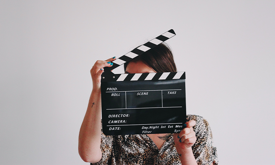 woman holding clapperboard in front of her face