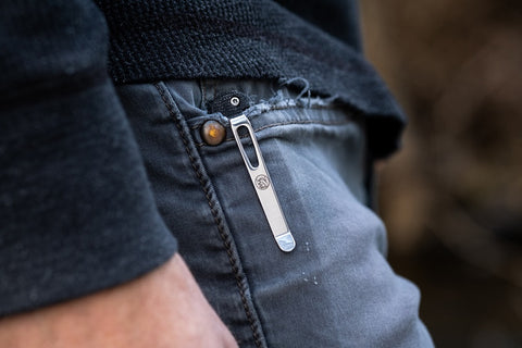 Close-up of a sleek silver Vosteed EDC knife with a pocket clip securely attached to a jeans pocket for everyday carry