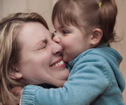 A baby gives a kiss to her mom