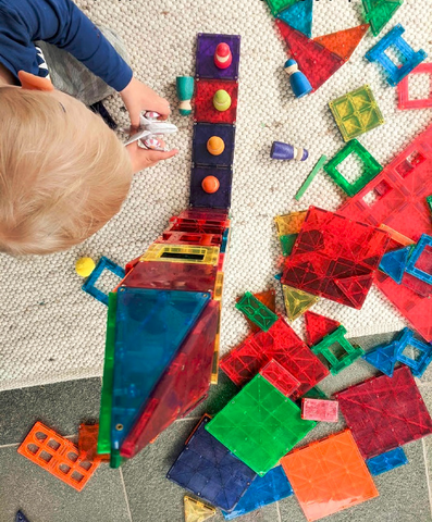 A kid is building a house with magnetic tiles