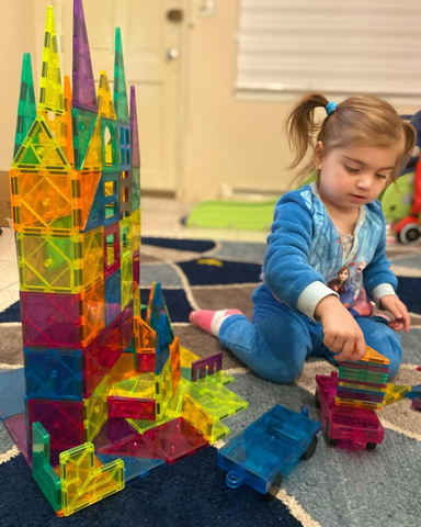 A baby is building a castle with Cossy magnetic tiles