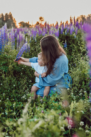 A woman is enjoying flowers with baby