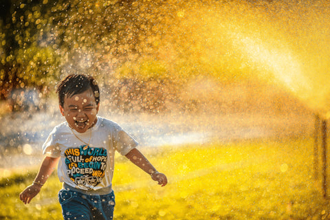 A little boy is playing with water in autumn sun