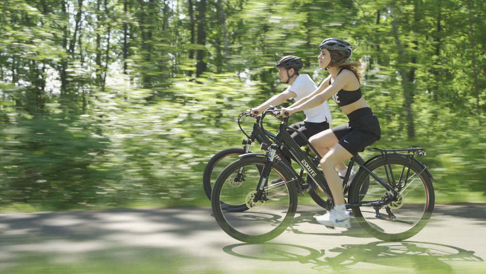 een man en een vrouw met helmen fietsen op het schaduwrijke pad e-bikes zonder beperking