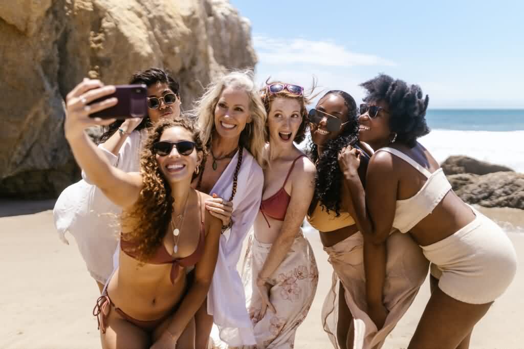 women taking group selfie at beach