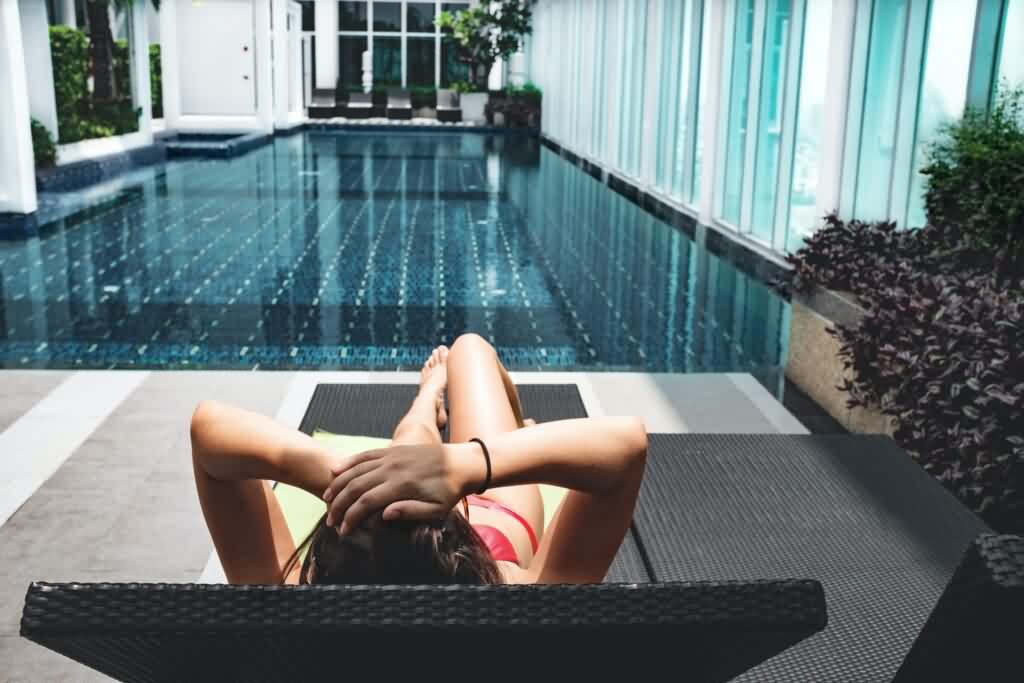 indoor pool lady in bikini rests on a bench