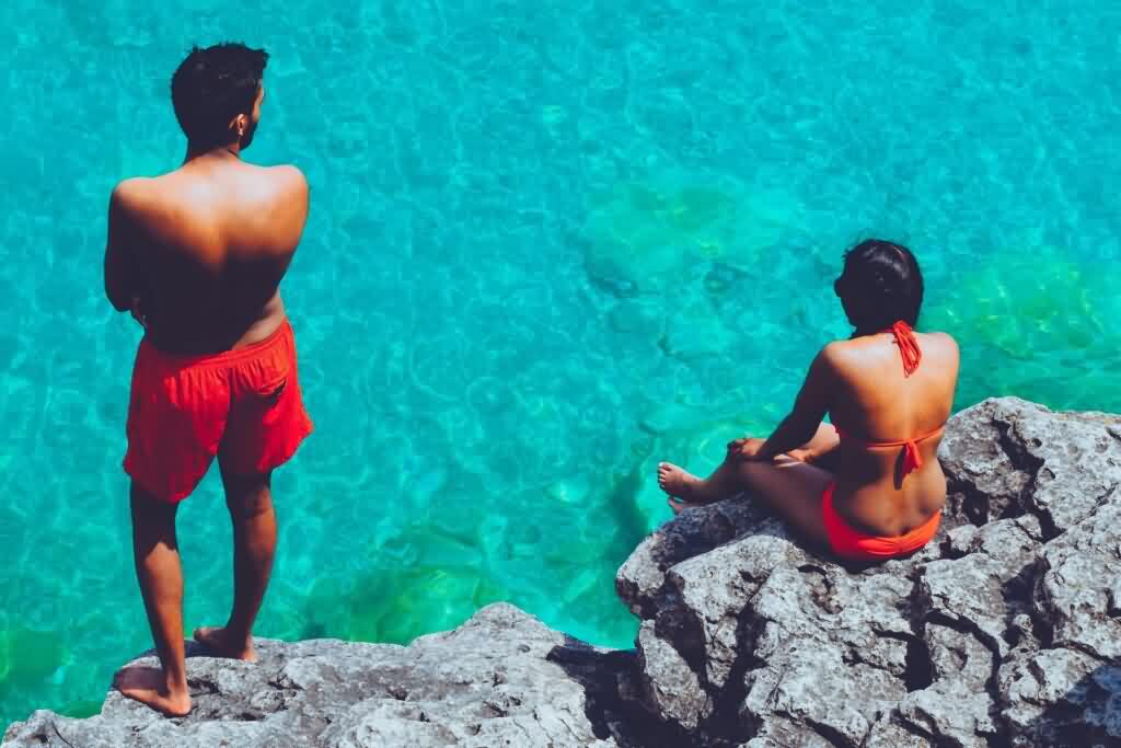 a couple in red swim suits in front of blue water