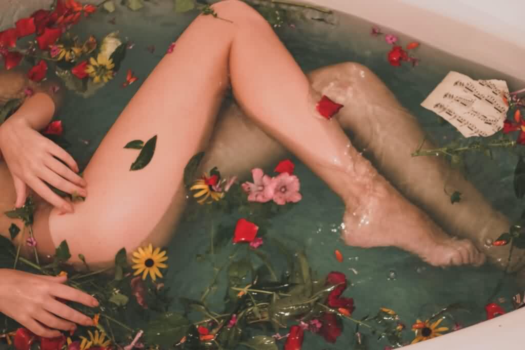 woman in bathtub shaving body hair