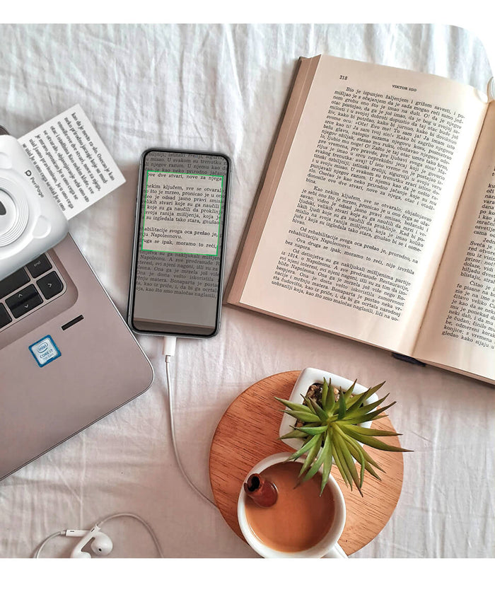 User printing notes from PeriPage 2" A6 Mini Printer while reading a book, perfect for study or personal use.