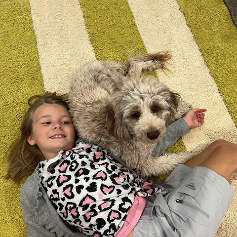 a girl and a dog lying down on the removable carpet tiles
