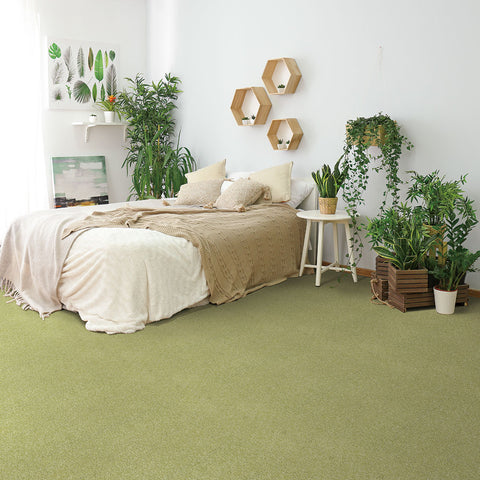 A bed is placed in a simple room with white walls, and then the entire room is covered in green Matace Removable Carpet Tiles!