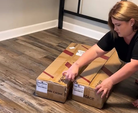 a women ready to open the box carried with Matace removable carpet tiles