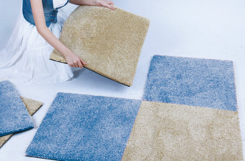 A woman is installing a carpet square that appears to be of very good quality.