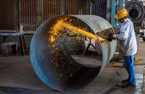 A welder is welding pipes in the workshop