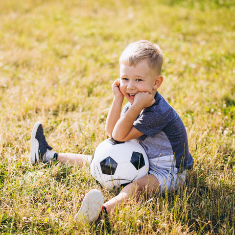 toddler playing soccer ball at the field