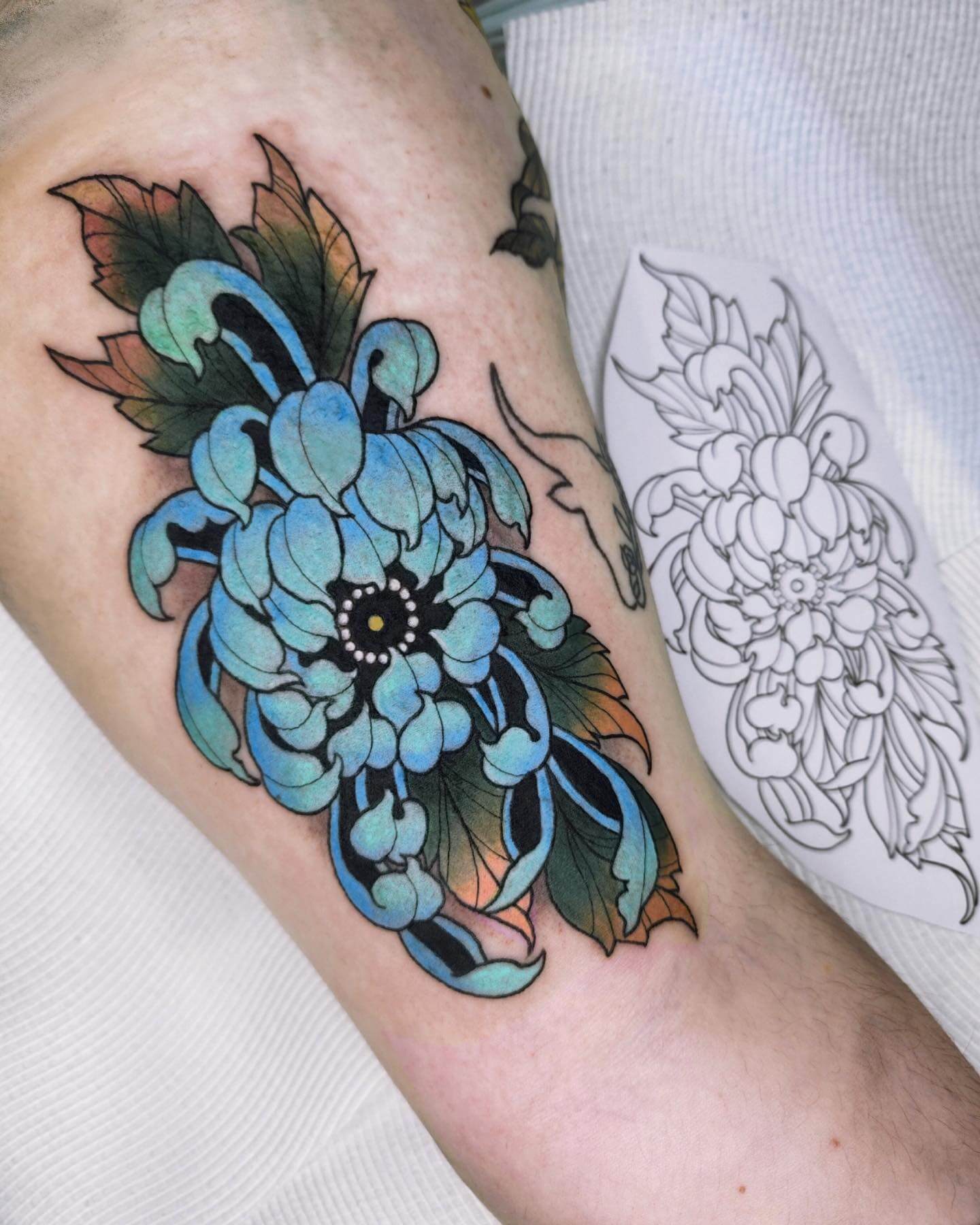 White chrysanthemum tattoo on the right inner forearm