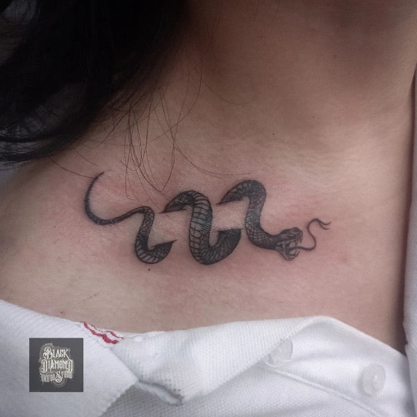 Snake and barbed wire tattoo on the right collarbone