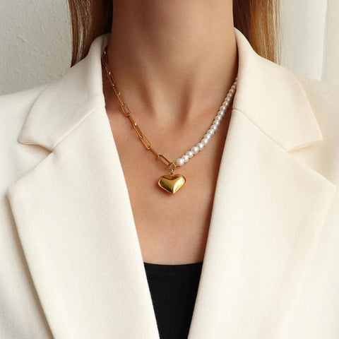 Women in white suit wear half gold half pearl necklace with heart.