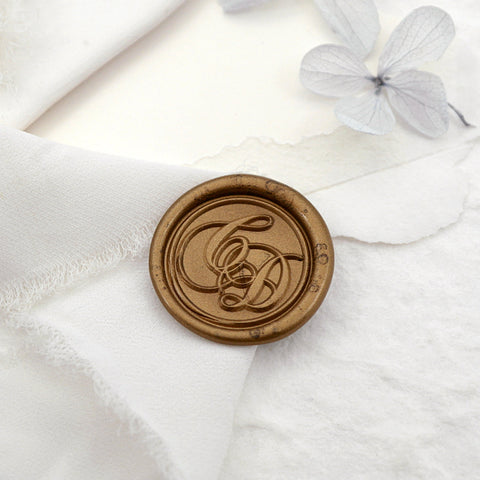 A wax seal with personalized calligraphy initials on the white cloth gift wrapping.