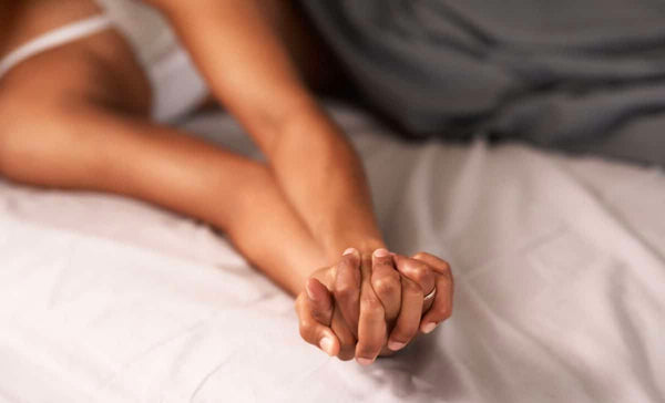 couple hold hands in bed