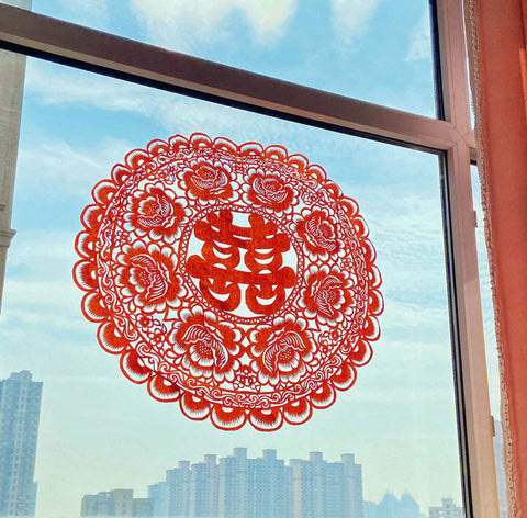 The character "囍" window flower is a Chinese paper-cut pattern used during weddings to symbolize joy and good fortune.