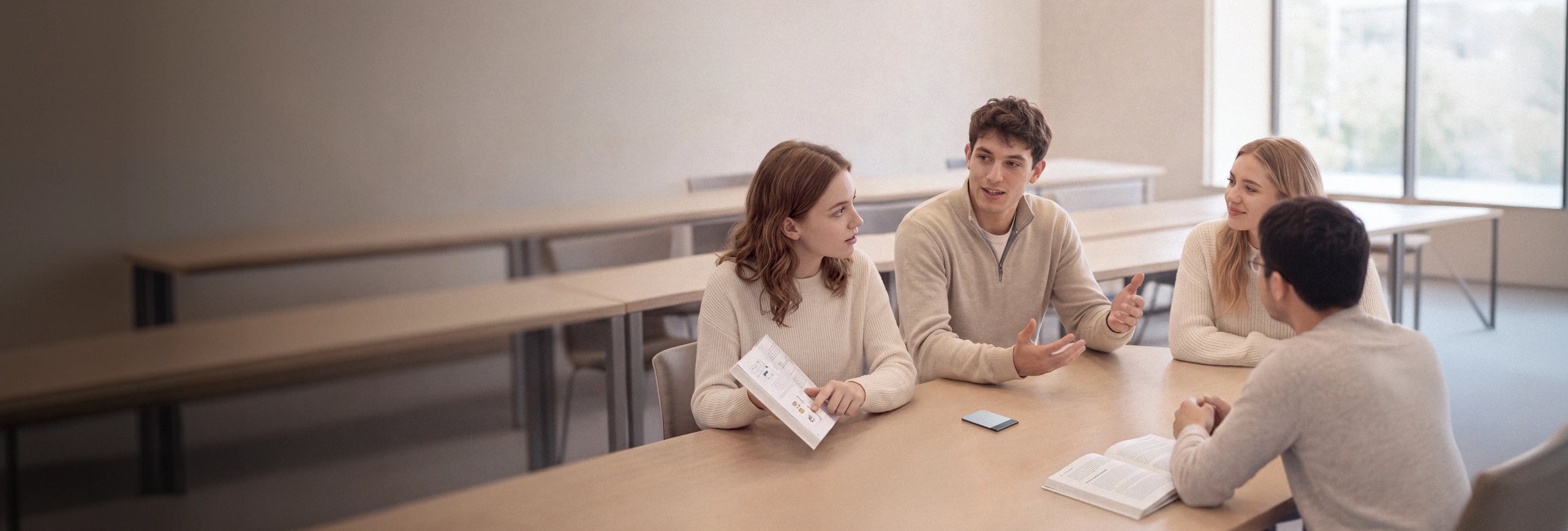 Four people sit around a table in a study hall with a blue Plaud Note recording their group discussion.